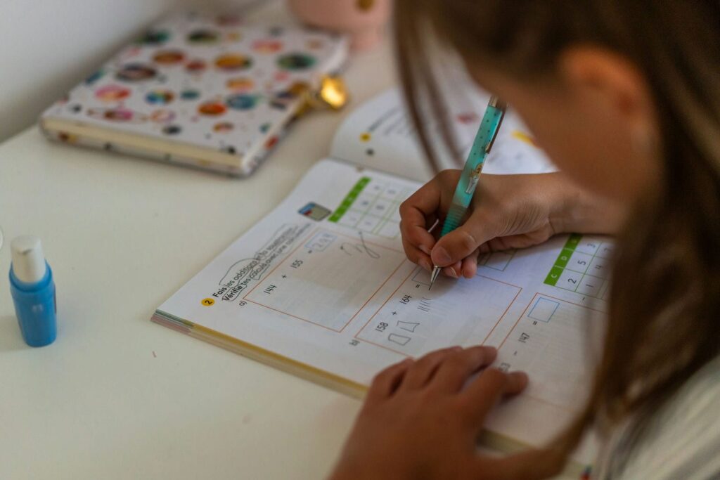 Elementary student working on a French math workbook, practising addition in French as part of integrated bilingual learning