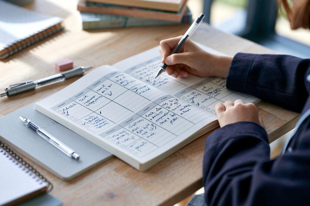 Grade 6 Montessori student in uniform using a modern personal planner to develop time management skills for high school