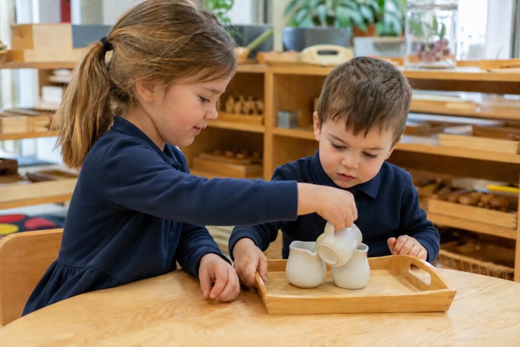 Five-year-old showing a three-year-old how to use a wooden Montessori tray at a shared table