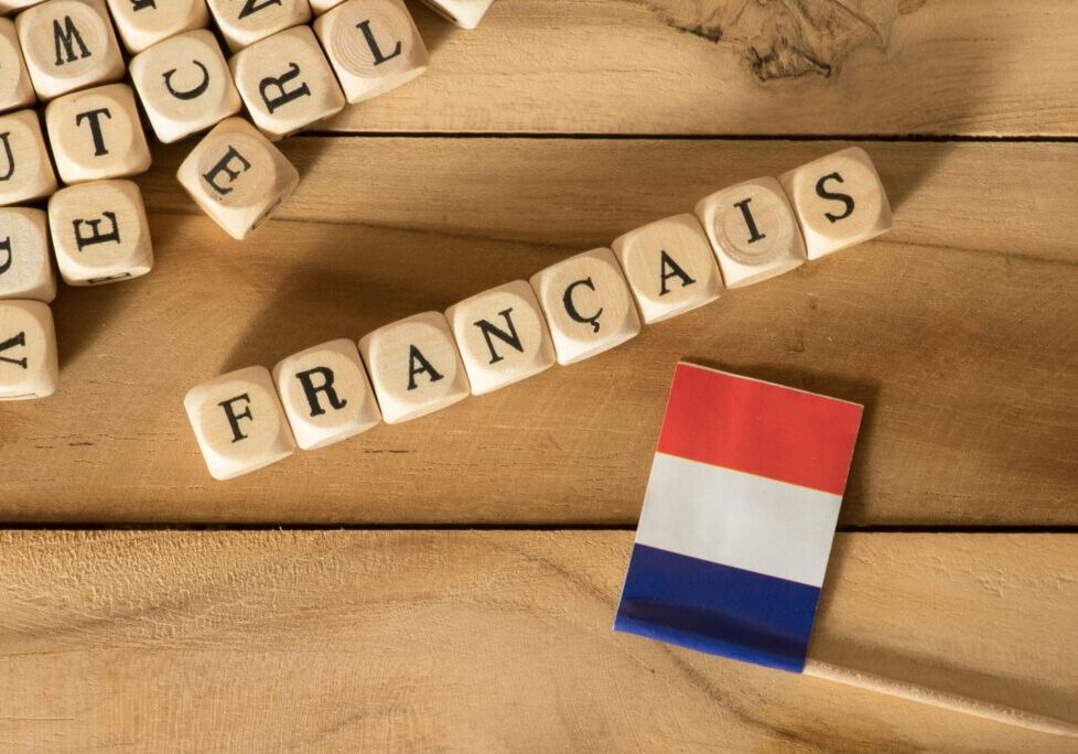 Wooden letter blocks spelling Français next to a French flag, representing French language learning in a Montessori environment